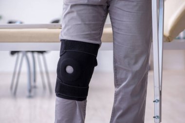 Koltuk değnekleriyle yaralı genç bir adam.