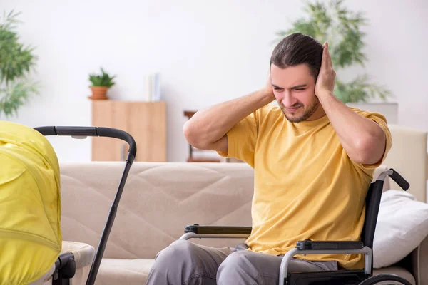 Jongeman aannemer in rolstoel op zoek naar pasgeborene — Stockfoto