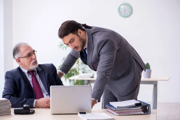 El viejo jefe y su joven asistente trabajando en la oficina — Foto de Stock