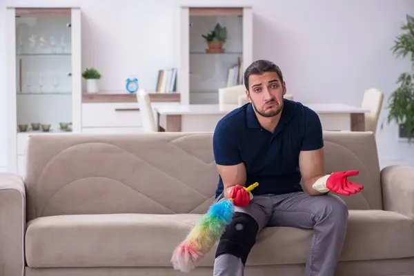 Young leg injured contractor cleaning the house — Stock Photo, Image