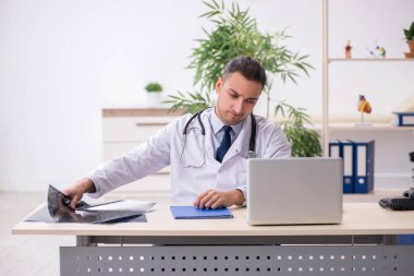 Klinikte çalışan genç erkek doktor.