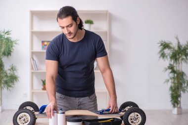 Kaykay tamir eden genç bir erkek tamirci.