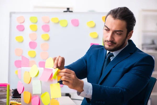 Ung manlig anställd i motstridiga prioriteringar koncept — Stockfoto