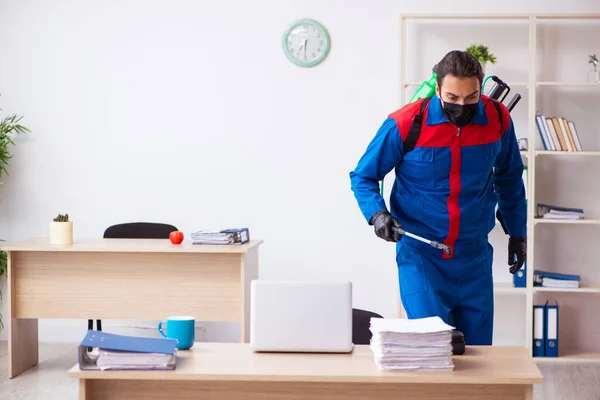 Young male contractor disinfecting office