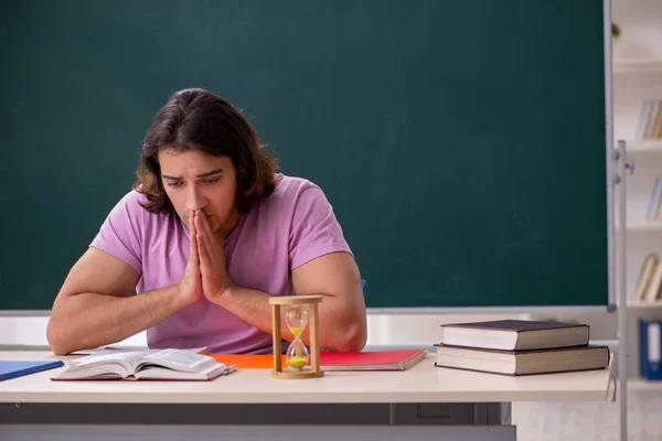 Joven estudiante masculino en el aula en el concepto de gestión del tiempo — Foto de Stock