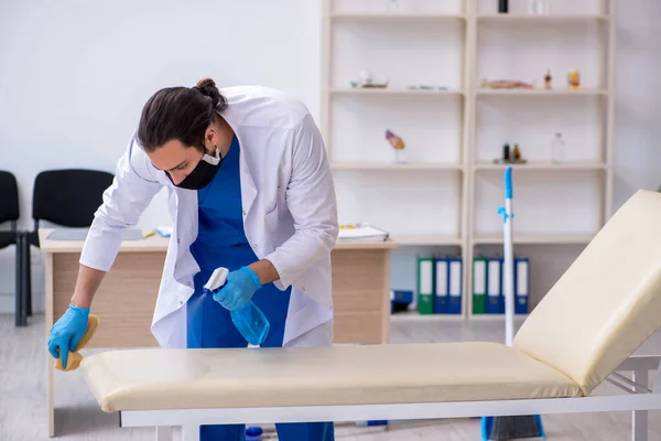 Junger männlicher Auftragnehmer desinfiziert Klinik im Pandemiekonzept — Stockfoto