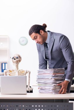 Genç erkek çalışan ve iskelet ofiste.