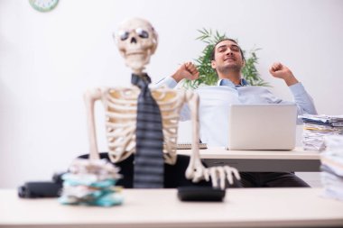 Genç erkek çalışan ve iskelet ofiste.