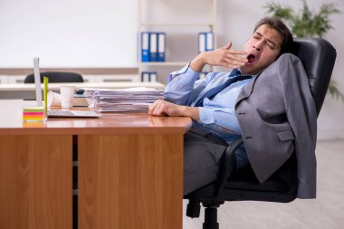 Genç erkek çalışan ofiste uyuyor.