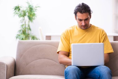 Evde bilgisayarı olan genç ve yakışıklı bir adam.