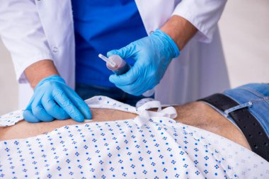 Yaşlı adam genç erkek stajyer doktoru ziyaret ediyor.