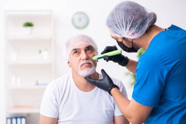 Yaşlı adam estetik ameliyat için erkek doktoru ziyaret ediyor.