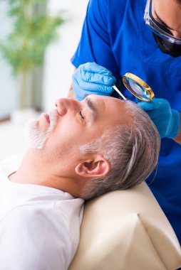 Yaşlı adam saç nakli için genç erkek doktoru ziyaret ediyor.