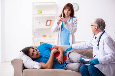 İki doktor hasta bir genci ziyaret ediyor.