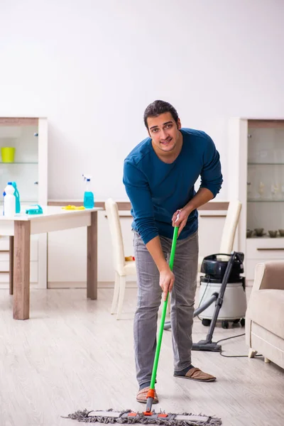 Jovem marido fazendo tarefas domésticas em casa — Fotografia de Stock