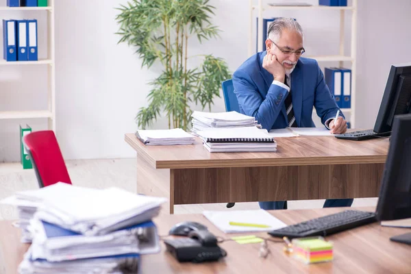 Velho empregado masculino e excesso de trabalho no escritório — Fotografia de Stock