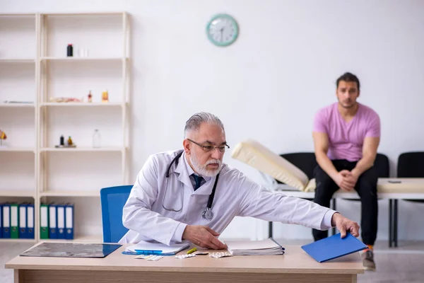 Genç erkek hasta yaşlı erkek doktoru ziyaret ediyor. — Stok fotoğraf