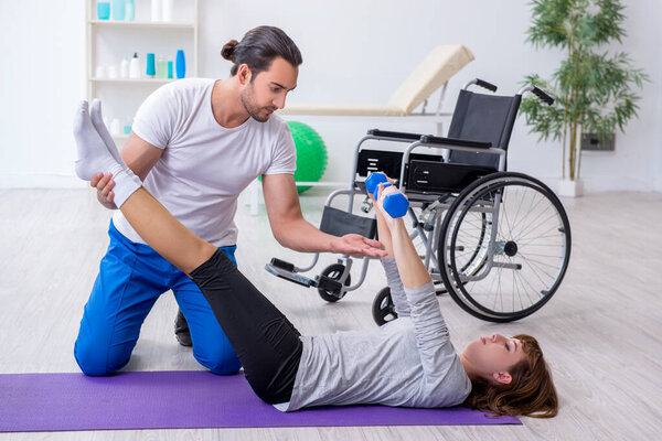 Женщина в инвалидной коляске делает спортивные упражнения с личным тренером
