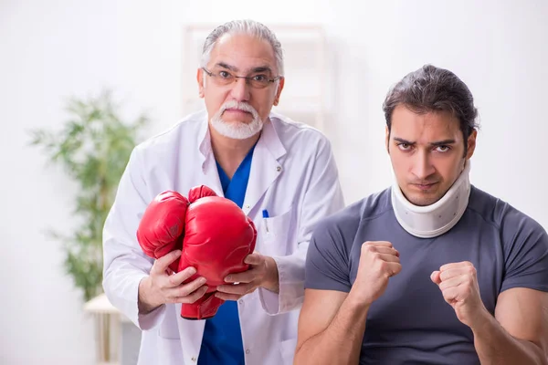 Genç yaralı boksör yaşlı doktor travmatoloğu ziyaret ediyor. — Stok fotoğraf