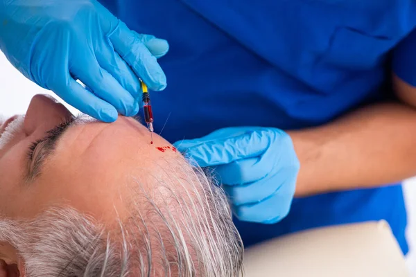 Old man visiting young male doctor in hair transplantation conce — Stock Photo, Image