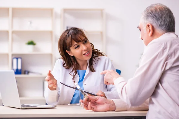 Old man visiting young female doctor for plastic surgery — Stock Photo, Image