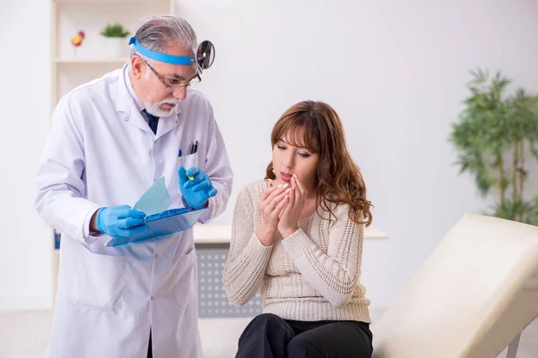 Giovane donna in visita vecchio medico maschio otorinolaringoiatra — Foto Stock