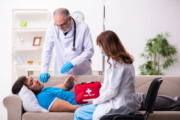 İki doktor hasta bir genci ziyaret ediyor.