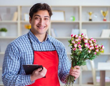 Çiçekçi asistanı bir demet çiçek veriyor.