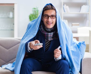 Çalışan işadamı grip olmuşken televizyon izliyor.