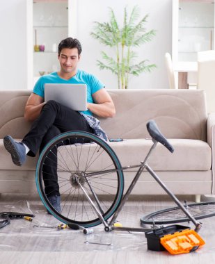 Evde bisiklet tamir eden genç bir adam.