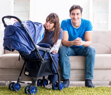 Bebekleri bebek arabasında oturan genç ebeveynler.