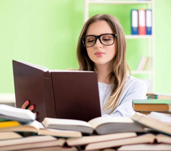 Jonge vrouwelijke student bereidt zich voor op examens met veel boeken — Stockfoto