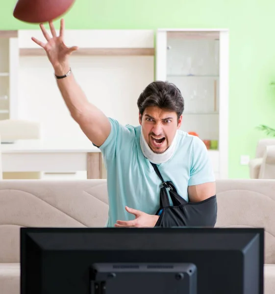Man with neck and arm injury watching american football on tv