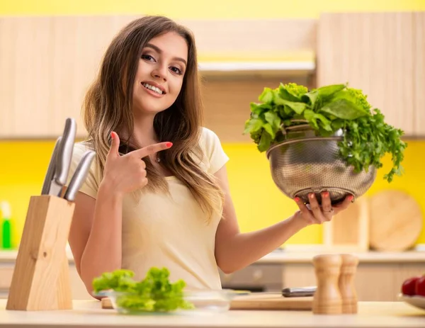 Jovem mulher preparando salada em casa na cozinha — Fotografia de Stock