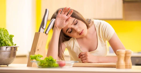 Jovem mulher preparando salada em casa na cozinha — Fotografia de Stock