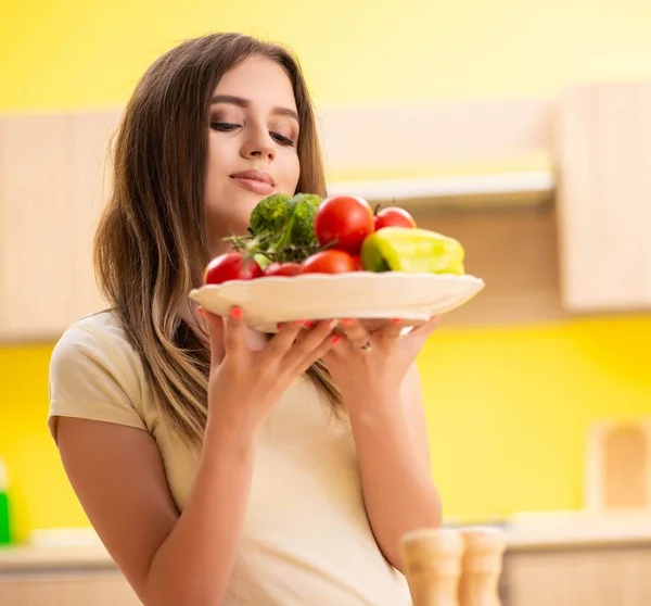 Jonge vrouw bereidt salade thuis in de keuken — Stockfoto