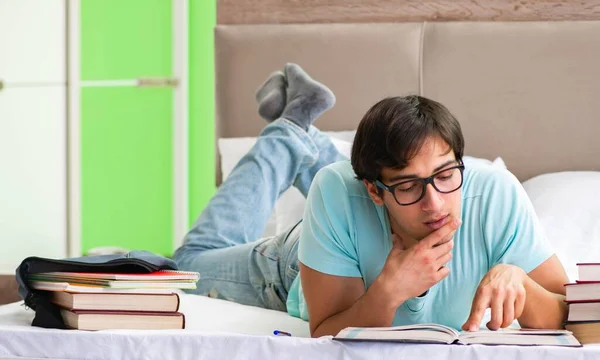 Studerande förbereder sig för tentamen hemma i sovrummet liggande på sängen — Stockfoto