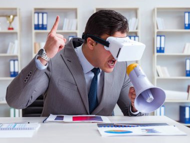 Ofiste sanal gerçeklik gözlüklü bir iş adamı var.
