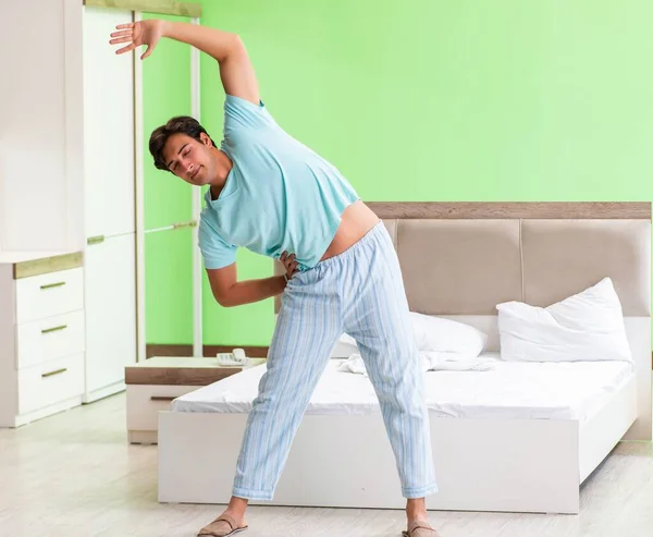 Joven en pijama haciendo ejercicios matutinos — Foto de Stock