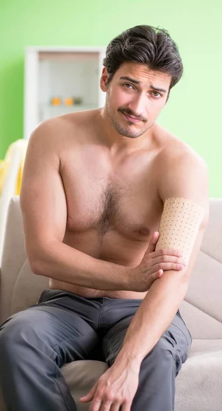Mann trägt Paprika-Pflaster zur Schmerzlinderung auf — Stockfoto