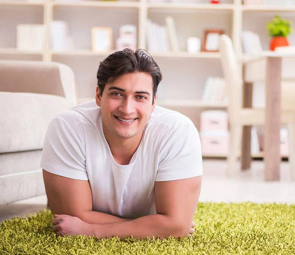 Jovem homem bonito feliz no chão do tapete — Fotografia de Stock