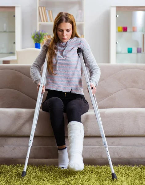 Mujer joven con la pierna rota en casa — Foto de Stock