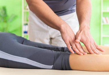 Genç doktor masör hastaya masaj yapıyor.
