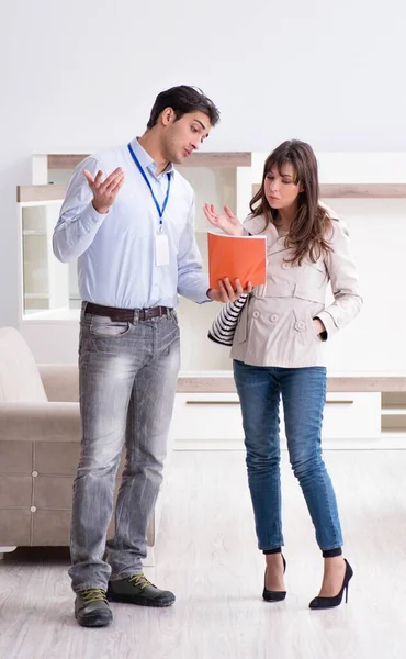 Vendedor explicando a la mujer cliente en la tienda de muebles — Foto de Stock