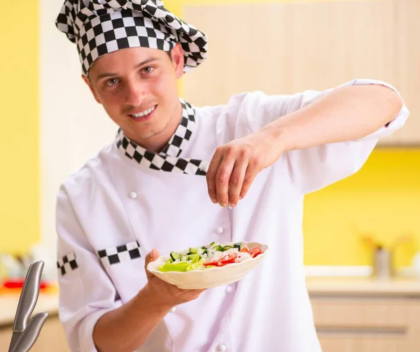 Jovem cozinheiro profissional preparando salada na cozinha — Fotografia de Stock