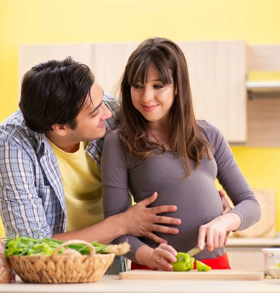 Man och gravid kvinna tillagar sallad i köket — Stockfoto