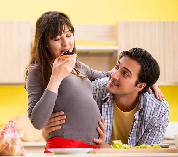 Man och gravid kvinna tillagar sallad i köket — Stockfoto