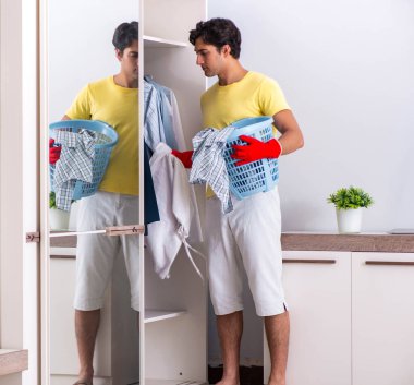 Genç yakışıklı adam yatak odasını temizliyor.