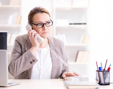 İş kadını çalışan ofis telefonundan konuşuyor.