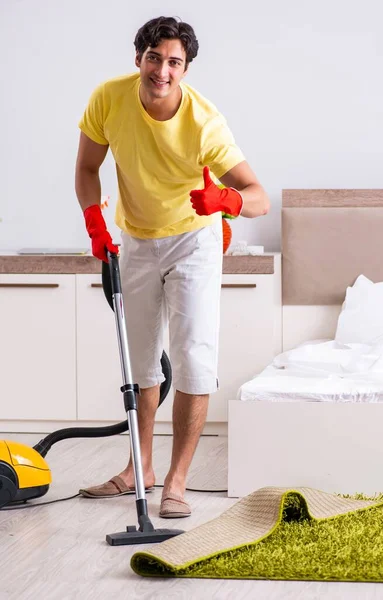 Joven hombre guapo limpieza en el dormitorio — Foto de Stock